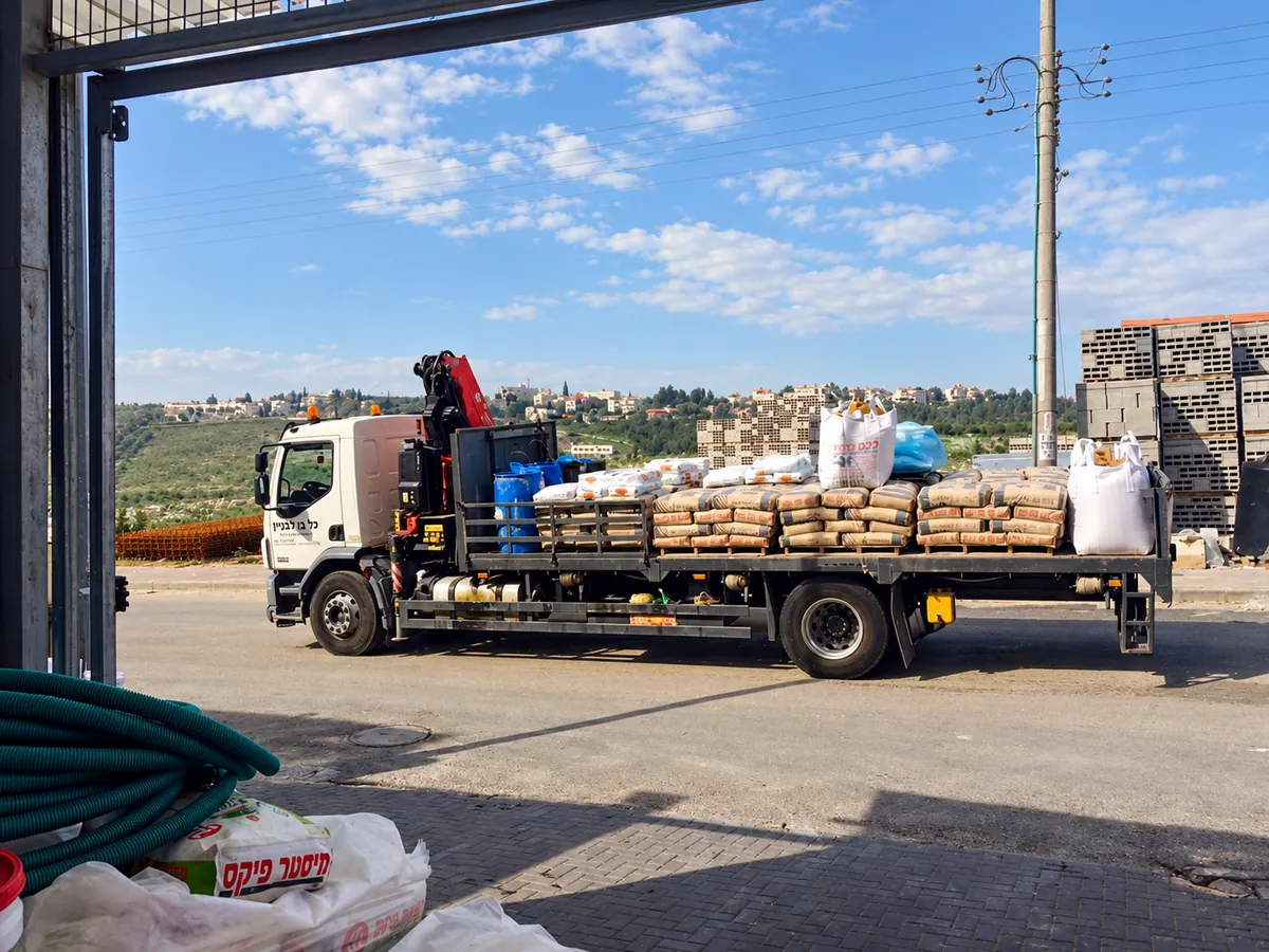 A flatbed crane truck loaded with cement bags and big bags